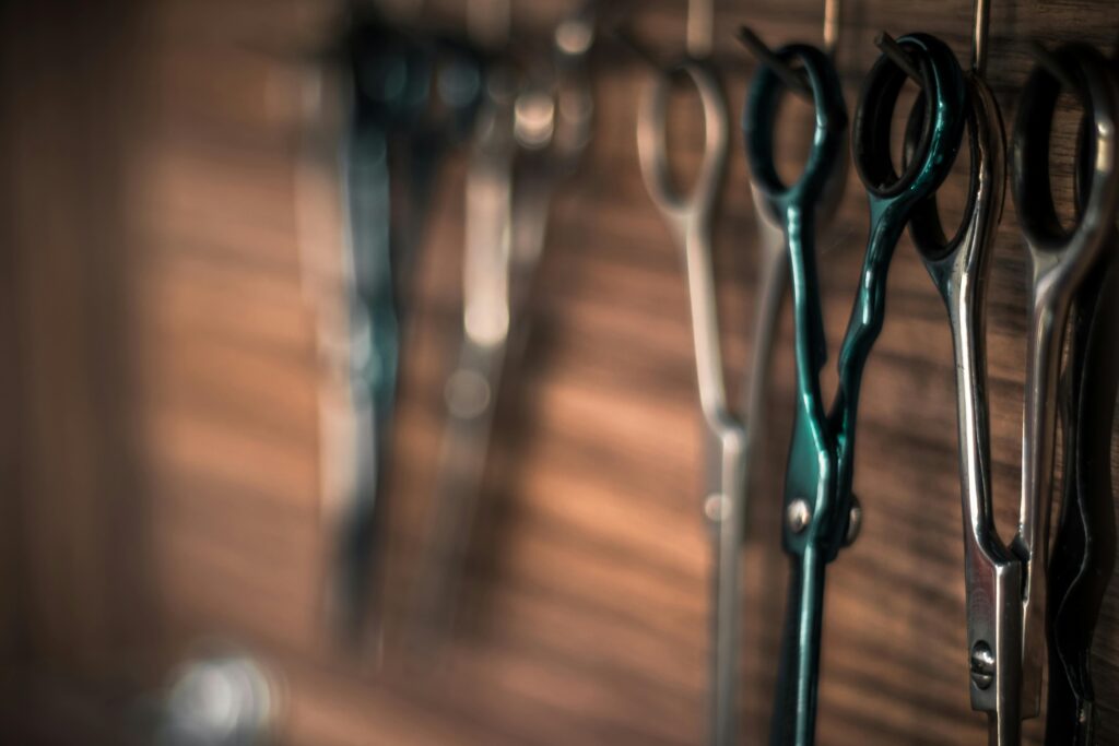 A detailed view of professional haircutting scissors hanging on a wooden wall in a barbershop.