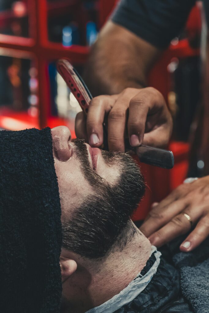 A barber skillfully shaves a man